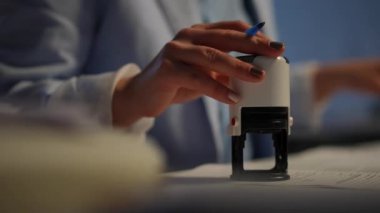 Unrecognizable businesswoman stamping signing documents in office indoors. Close-up round seal in female hand. Successful confident Caucasian woman working with paperwork