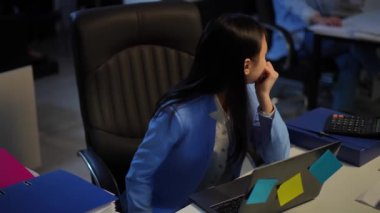 High angle view careless Asian slim young woman looking back at unrecognizable Caucasian manager putting on VR headset smiling. Relaxed happy employee enjoying augmented reality at workplace