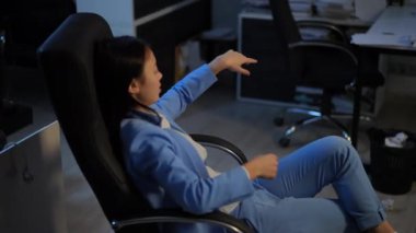 Young Asian woman throwing away trash in waste bin pushing chair to table in office. Female employee working indoors with paperwork making mistake. Business and lifestyle