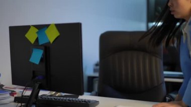 Hurrying troubled Asian woman entering office checking e-mail on computer with stressed facial expression. Portrait of young overworking manager messaging online at workplace. Business load concept