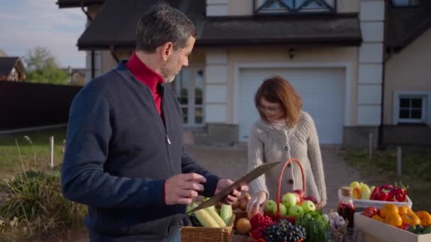 Focused Handsome Man Examining List Woman Sorting Fruits Vegetables Table — Vídeo de stock