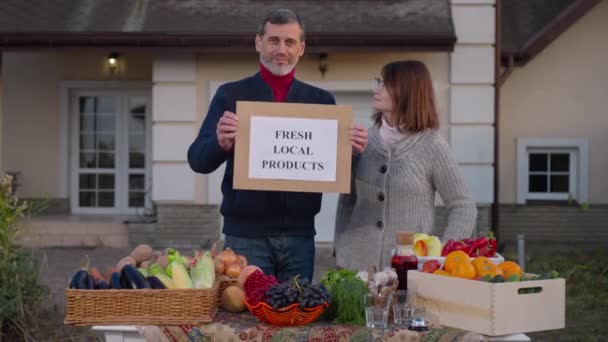 Happy Couple Advertising Fresh Local Products Standing Farm Market Outdoors — Stockvideo