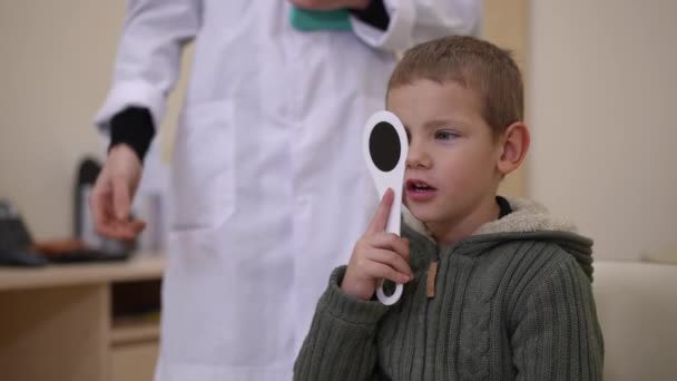 Little Boy Closing One Eye Occluder Looking Away Talking Unrecognizable — Video Stock