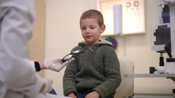 Little Caucasian Boy Sitting Ophthalmological Appointment Refusing Eyeglasses Unrecognizable Doctor — Stock Video