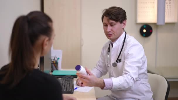 Уверенный Себе Врач Рекомендует Эффективные Лекарства Пациенту Сидящему Столом Больнице — стоковое видео