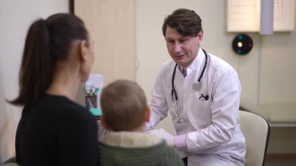 Portrait Smiling Doctor Talking Little Boy Young Woman Hospital Filling — Vídeo de Stock