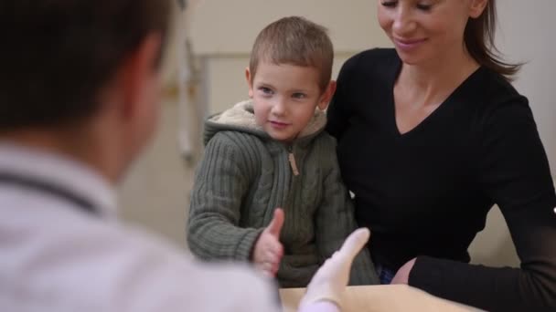 Joyful Little Boy Gesturing High Five Doctor Sitting Mother Hospital — ストック動画