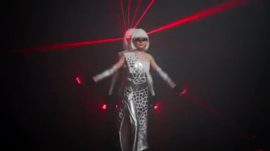 Charming slim Caucasian women in stage costumes with red laser beam performing on stage at black background. Smiling confident talented performers dancing modern art dance