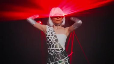 Medium shot portrait of woman in cyber costume with red laser beam dancing on stage posing. Caucasian professional female dancer performing at black background with neon light on eyeglasses