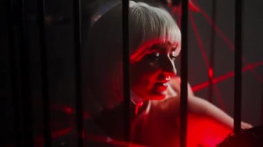 Close-up two women dancing with red neon light in cage at black background. Professional talented female Caucasian dancers performing in slow motion on stage. Choreography and art concept