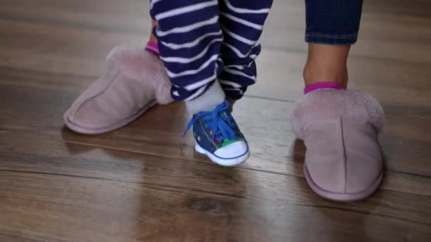 子供を助ける認識できない女性との最初のステップを作るスニーカーの小さな赤ちゃんの足 積極的な白人の幼児歩くとともに母親室内で上の寄木細工の床に家 — ストック動画