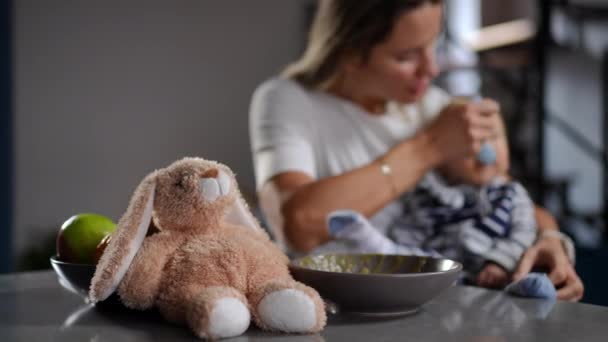 Close Toy Left Blurred Mother Feeding Infant Background Caucasian Woman — Vídeos de Stock