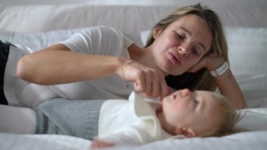 Portrait of loving mother lying on bed with blurred baby girl talking caressing face of curios kid. Happy confident Caucasian woman enjoying tranquility with toddler daughter in bedroom indoors