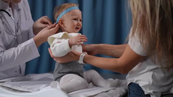 Dissatisfied Baby Girl Sitting Hospital Looking Mother Doctor Measuring Head — Stockvideo