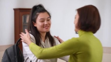 Genç Asyalı kız kameraya bakıp beyaz psikologa sarılıyor. Profesyonel psikanalistle evde poz veren tatmin olmuş genç bir hastanın portresi. Psikoterapi verimliliği kavramı