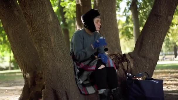沮丧的无家可归的女人坐在公园的树上思考着如何做手势 城市公园里被毁的白人无房人士的画像 社会问题概念 — 图库视频影像