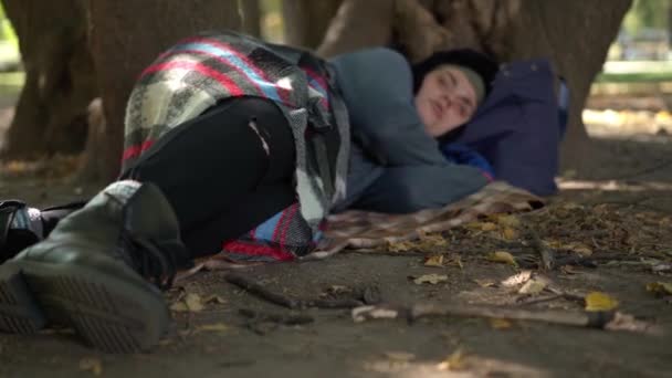 城市公园里睡在树下的无家可归的年轻妇女的特写腿 疲惫的白种人流浪汉躺在户外的草地上 躺在绿草上 无家可归和社会问题 — 图库视频影像
