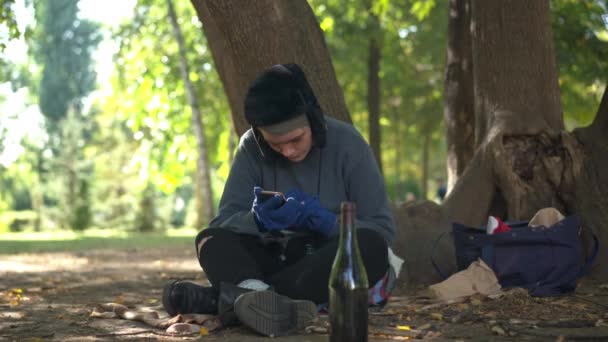 Młoda Biała Bezdomna Kobieta Używająca Smartfona Siedzącego Bagażniku Drzewa Letnim — Wideo stockowe