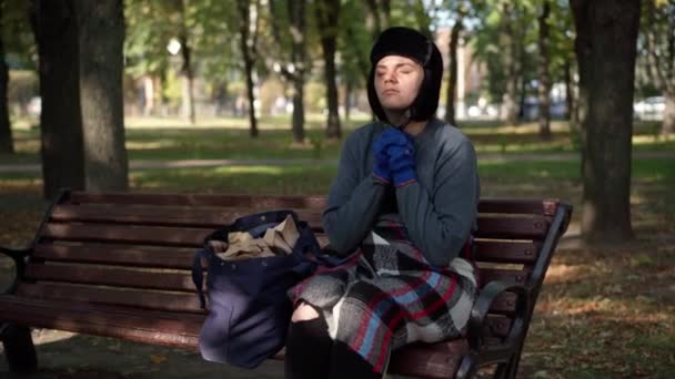 目を閉じて祈る無力なホームレスの女性の肖像画と手は日当たりの良い公園のベンチに座っていた 助けを求める絶望的な悲しい白人のトランプの中景 — ストック動画