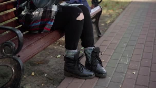 公園のベンチに座っている鳥のためにパンを投げる認識できないホームレスの女性 足のない白人若いです女性給餌ハトオン路地屋外 — ストック動画