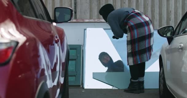バックビューホームレスの女性は悲しい顔の表情を持つ窓ガラスの反射を見てください 屋外の都市駐車場のゴミに反映若い白人の浮浪者 スローモーション シネマ4K Prores — ストック動画