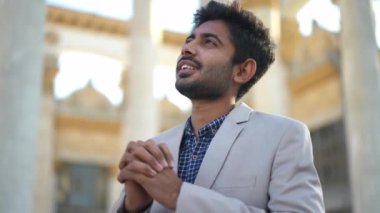 Orta Doğulu genç bir adam el ele tutuşup dışarıda el ele konuşuyor. Şehir caddesinde beyaz ceketli, kendine güvenen yakışıklı bir adamın Tanrı 'ya teşekkür edişinin portresi. Yaşam tarzı ve din