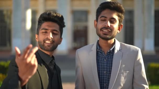 2人の自信に満ちた成功した中東の若い男性が屋外に立ってカメラを見て話しています フロントビューポートレートのハンサムなビジネスマンのブログ上の都市の街のポーズ — ストック動画