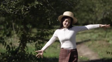 Genç ve mutlu bir kadın, güneş ışığının altında elleri gergin bir şekilde ağır çekimde yürümeye başlıyor. Sunny Park 'ta dolaşıp gülümseyen Asyalı pozitif kadının portresi. Boş zaman ve eğlence kavramı