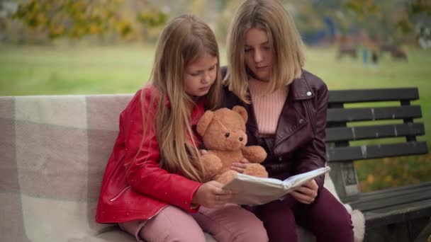 Dwie Skoncentrowane Nastolatki Misiaczkiem Czytające Książkę Ławce Parku Piękne Białe — Wideo stockowe