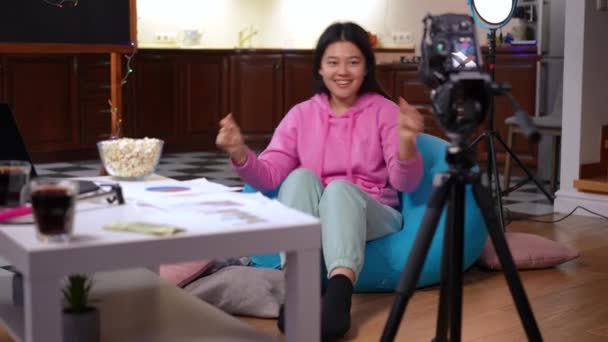 自信快乐的年轻亚洲女孩笑着坐在袋椅上拍摄视频博客 快乐少年博主在客厅里用相机记录舞蹈的肖像 生活方式和技术 — 图库视频影像