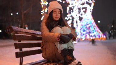 Depresyondaki Asyalı genç kız Noel gecesi dışarıda bankta oturmuş dizlerine sarılıyor. Şehir sokaklarında yeni yıl aydınlatmasıyla hayal kırıklığına uğramış yalnız bir gencin portresi.