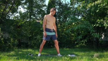 Savaşçı kılığına girmiş beyaz bir adam gün ışığında açık havada antrenman yapıyor. Kendine güvenen erkek yoginin portresi güneşli arka bahçede yeşil çayırda dizüstü bilgisayarla egzersiz yapıyor. Sağlıklı yaşam tarzı