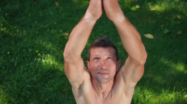 Yüksek açılı beyaz adam portresi. Kollarını uzatıyordu. Nilüfer çiçeğiyle meditasyon yaparken el ele tutuşuyordu. Yavaş çekimde yeşil çimlerde egzersiz yapan kendine güvenen yogi.