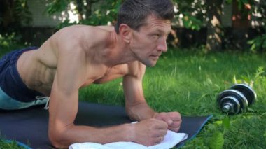 Yan görünüş dayanıklı sporcu tahta pozisyonu alıyor. Dışarıya bakarak egzersiz yapıyor. Kendine güveni tam beyaz bir adam yazın arka bahçede çalışıyor. Spor ve sağlıklı yaşam tarzı kavramı