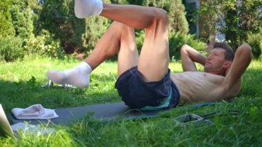 Yan manzara sporcusu arka bahçede bisiklet egzersizi yapıyor. Kafkas formundaki sporcu güneşli bir günde dışarıda bacak kaslarını çalıştırıyor. Fitness ve sağlıklı yaşam tarzı