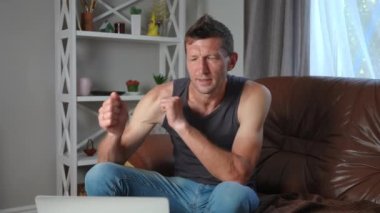 Dizüstü bilgisayarda çalan olumlu adam yavaş çekimde dans ediyor oturma odasında kanepede oturuyor. Uzaktan kumandayla evde çalışmaktan hoşlanan kendinden emin Kafkasyalı bir ressam portresi