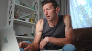 Dizüstü bilgisayarda yavaş çekimde kalemle internette sörf yapan konsantre bir adam. Kafkasyalı serbest çalışan yetişkin bir adamın portresi. İç mekanda çalışıyor ve düşünüyor. Yaşam tarzı ve serbest çalışma