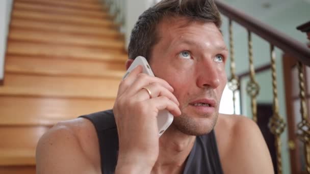 Крупный План Положительный Человек Разговаривает Телефону Смеясь Сидя Лестнице Гостиной — стоковое видео