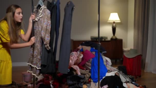 Zmęczona Nastolatka Przechodząca Wieszakiem Ubrania Salonie Kupą Używanych Używanych Ubrań — Wideo stockowe