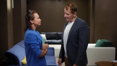 Yan görünüm pozitif satıcı ve alıcı kapalı bir mobilya dükkanında dikilirken konuşuyor. Zengin adamın yeni kanepe seçmesine yardım eden beyaz uzman kadının orta boy portresi. Tüketim ve yardım