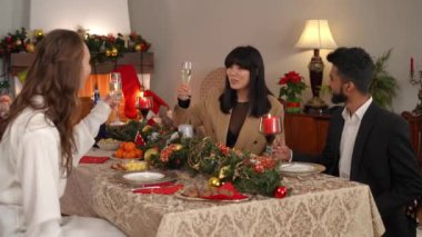 Kendine güvenen Asyalı kadın, kafkas ve Ortadoğulu arkadaşlarıyla şampanya tokuşturup alkol içiyor. Noel arifesini evde arkadaşlarıyla kutlayan mutlu bayanın portresi.