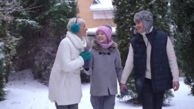 Karlı kış gününde el ele tutuşup gülerek konuşan mutlu beyaz erkek ve genç kız. Neşeli, rahat bir ailenin portresi. Arka bahçede soğuk bir günün tadını çıkarıyor.