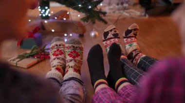 Olumlu bir ailenin omzunun üzerinden ateş etmek oturma odasında Noel ağacında oturmak çorapların içinde yeni yıl baskısı ile ayaklarını sallamak. Mutlu rahatlamış baba, anne ve kız tatilin tadını çıkarıyorlar.