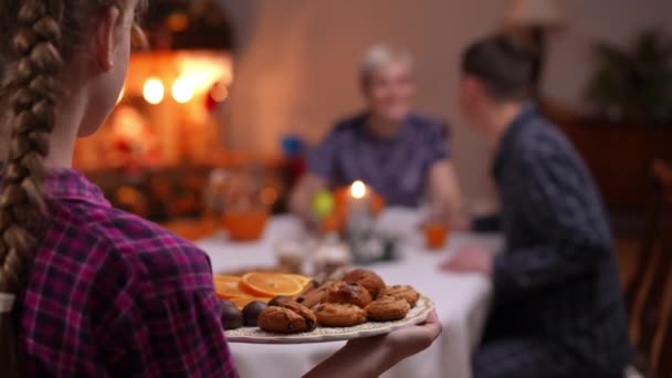 密切关注传统的新年甜糕点和水果在女性青少年的手中 模糊的男人和女人说话的背景 无法辨认的女儿和父母在家里庆祝圣诞节 — 图库视频影像