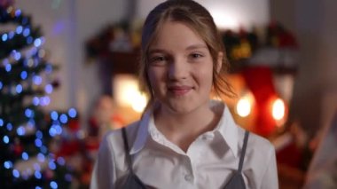 Yeni yıl arifesinde kameraya bakıp gülümseyen mutlu beyaz kızın vesikalığını yakınlaştır. Mutlu kendine güvenen genç Noel gecesi evde poz veriyor. Boş zaman ve tatiller