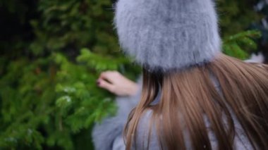 Arkaya bakan ince, köknar ağacı dallarını budama makası ile kesen genç bir kadın. Tanımlanamayan beyaz kadın ormanda yeni yıl çelengi için parça seçiyor.