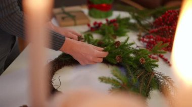 Önünde mumlar yanan el yapımı Noel çelengi yapan genç bir kadın. Tanımlanamayan Kafkasyalı kadın Noel arifesinde evde yeni yıl süsü yapıyor.