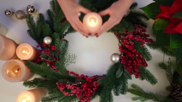 クリスマスリースと女性の手が真ん中に燃えるキャンドルを入れてトップビューテーブル 大晦日に家を飾る認識できないスリムな白人女性 スローモーション — ストック動画
