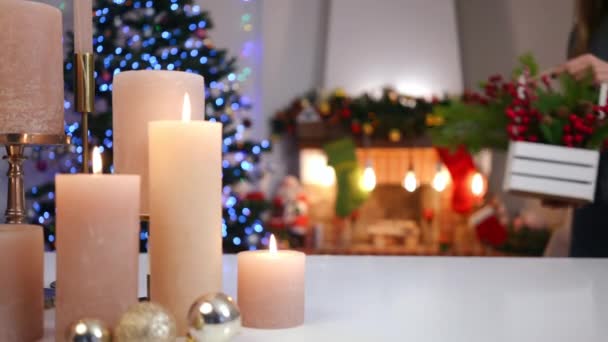 桌上放着燃烧的蜡烛和难以辨认的女人 把圣诞篮子放在节日前夕 新年前夕在客厅装饰家的苗条身材的小姐 — 图库视频影像