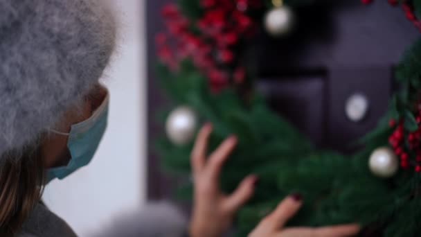 Зблизька Молода Жінка Ковід Обличчям Маска Доторкаючись Розмитого Різдвяного Вінка — стокове відео
